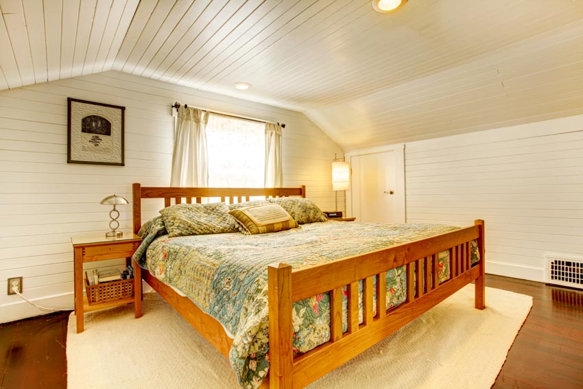 Bedroom with beadboard ceiling, bed, nightstand, window, wood floor, rug, and curtains