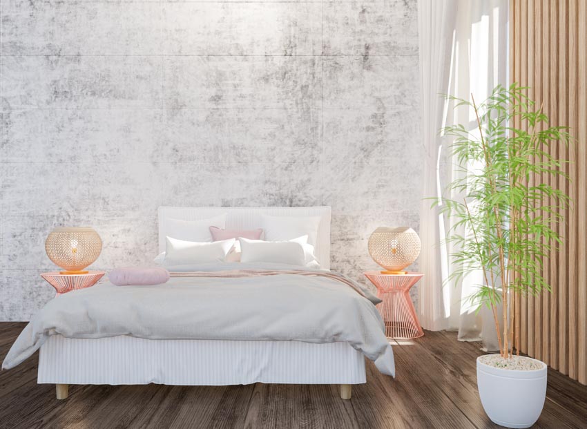 Bedroom with bed skirt, wood floor, comforter, pillows, stylish nightstands, indoor plants, and window curtains
