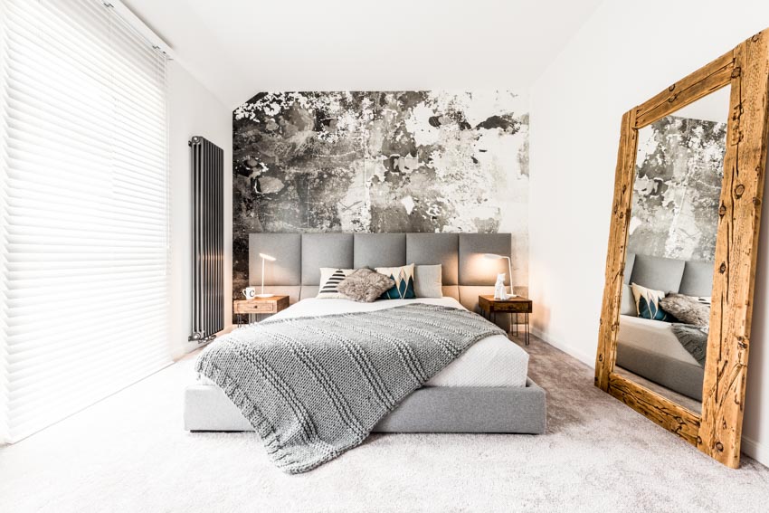 Bedroom with platform bed, knotty wood mirror, comforter, pillows, nightstands, lamps, and windows