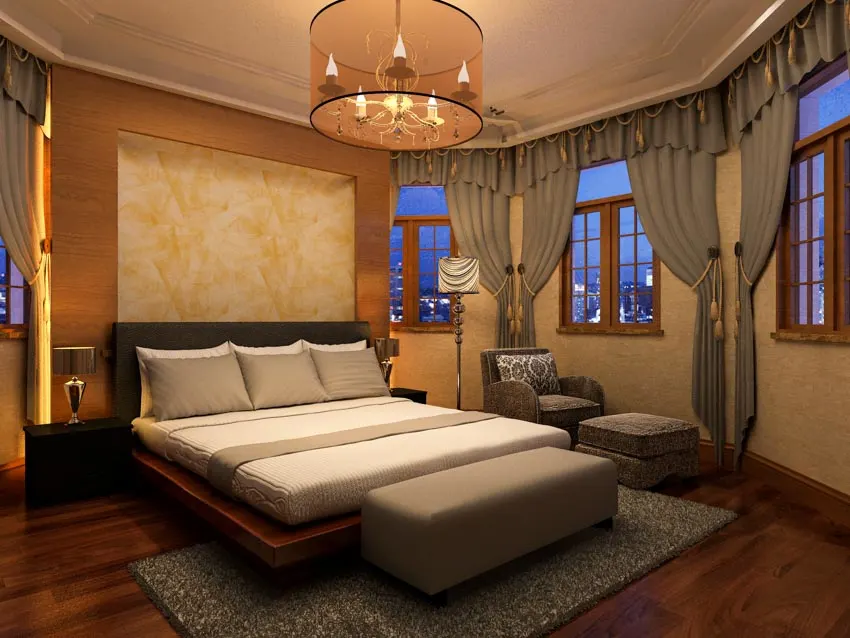 Bedroom with platform, mattress, headboard, ottoman, pillows, curtains, ceiling light, rug, wood floors, and windows