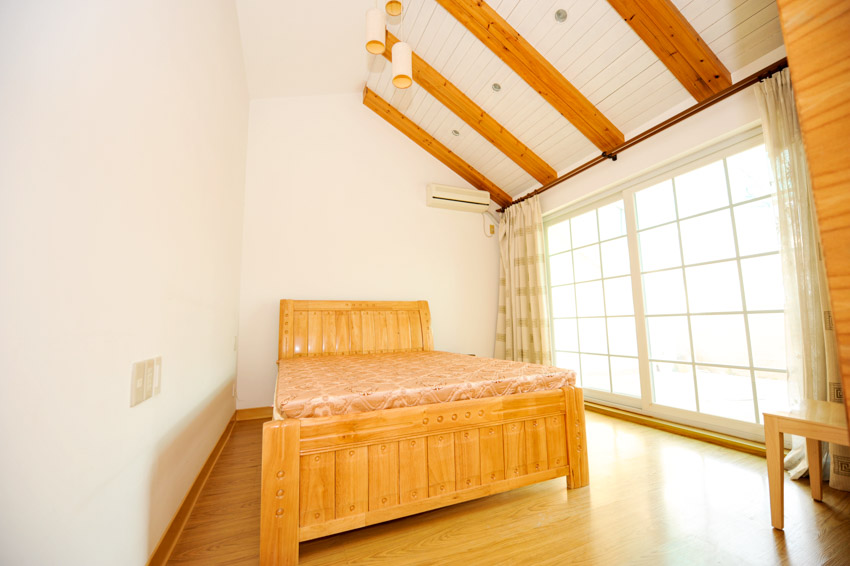Bedroom with wood framed bed, windows, wood flooring, and beadboard ceiling