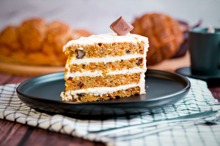 Black plate for dessert with a slice of carrot cake