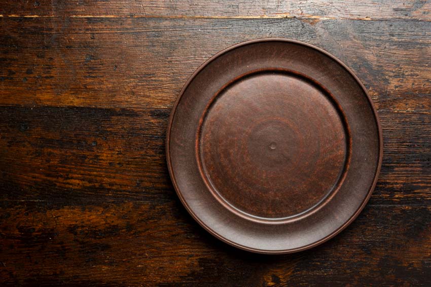 Brown earthenware plate on top of wood surface