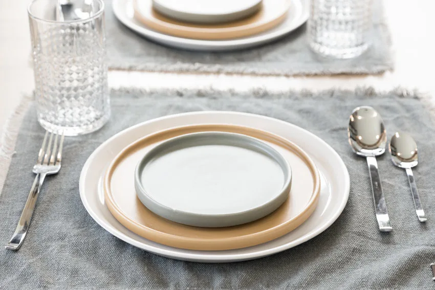 Plates made of ceramic placed on top of a grey cloth placemat