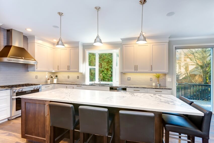 Kitchen with oven range, island with quartz countertop, chairs and pendant lights