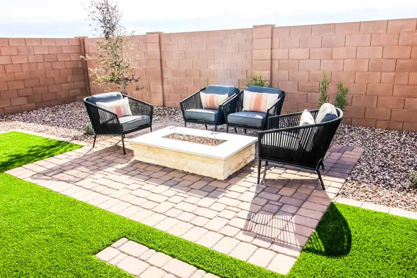 Decomposed granite and paver patio with fire pit, sofa chairs, and stone wall