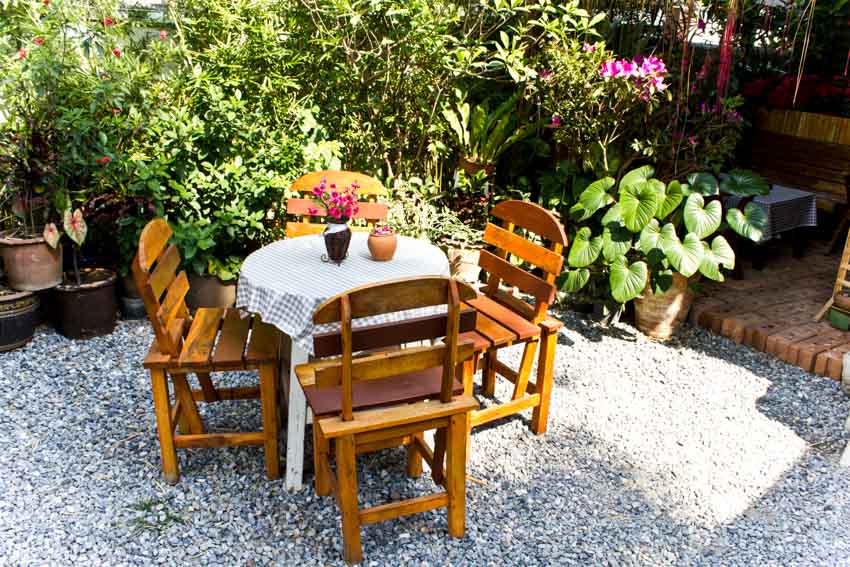 Decomposed granite patio with wood chairs, round table, and plants