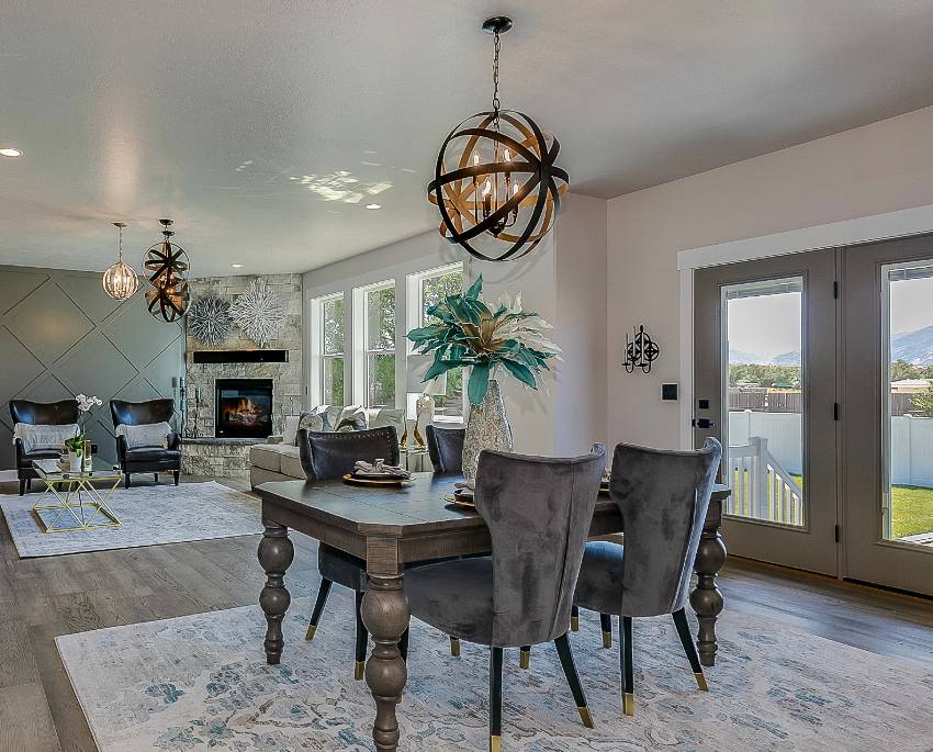 Dining area and family room with gray furnitures, wood tile flooring and globe chandeliers