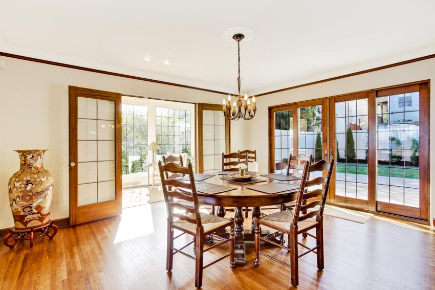 Dining room with french ladder back chairs, round table, wood floors, ceiling light, and glass door