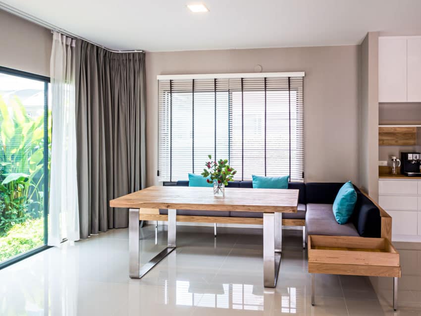 Dining room with quartz flooring, table, nook seating, window, glass door, and curtains