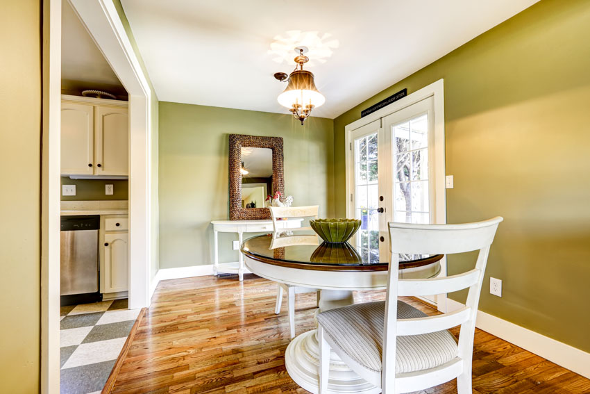 Dining room with table, chairs, olive painted walls, mirror, and glass door