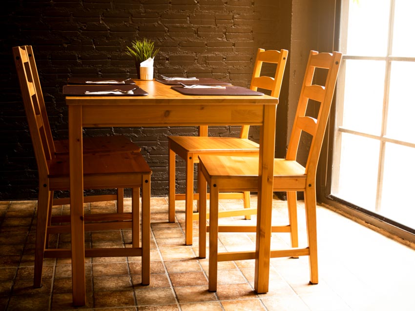 Dining room with table, ladder back chairs, brick wall, and window