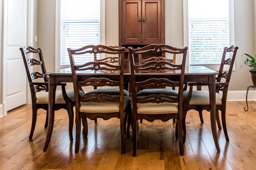 Dining table with armless ladder back chairs, table, windows, and wood plank floors