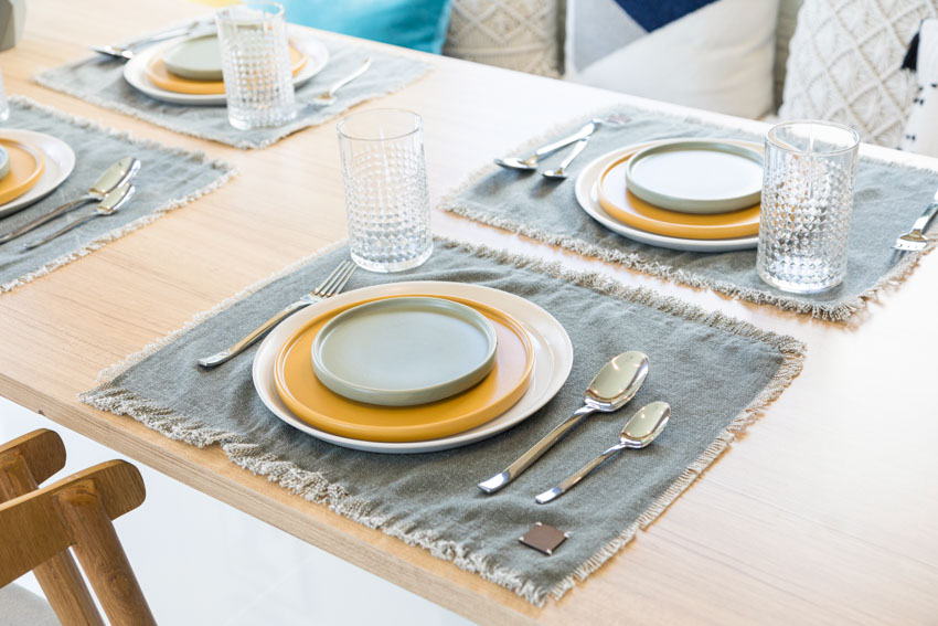Dining table with different types of plates, glasses, spoons, and forks