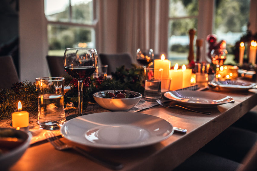 Dining table with dinner plate, candles, centerpieces, and wine glasses