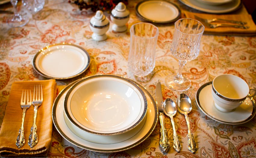 Dining table with soup and bowl plate, cups, glasses, forks, and spoons