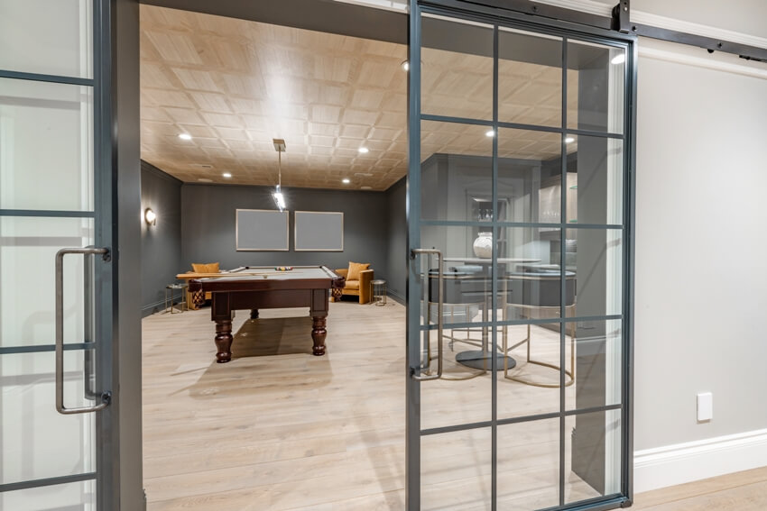 Family room with billiard table, chairs and sliding metal and glass doors