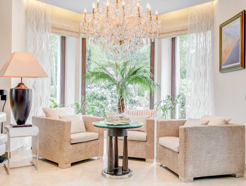 Fancy armchairs in the living room with bay window and crystal chandeliers