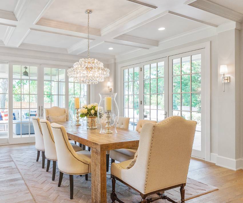Formal dining in spacious room with elegant crystal chandelier, French glass windows, coffered ceiling and wood floors