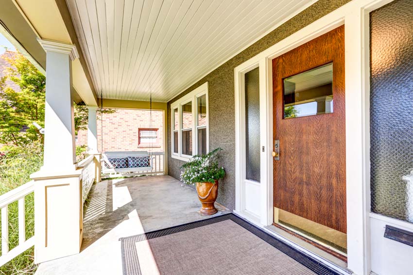 Front porch with PVC beadboard ceiling, wood door, and floor rug
