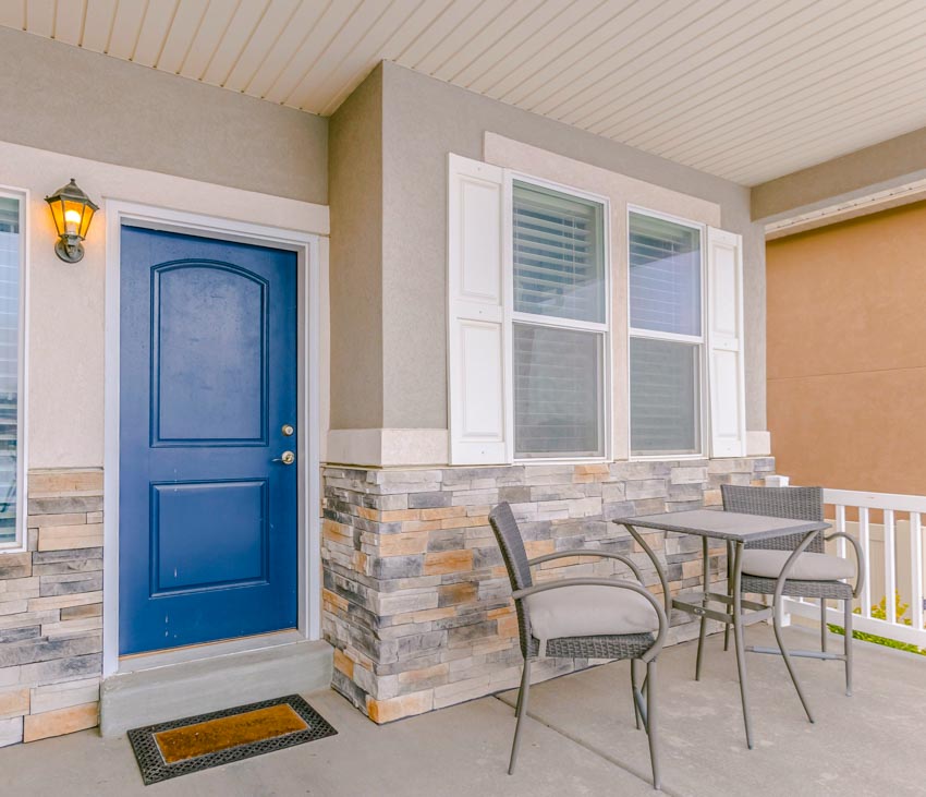 Front porch with beadboard ceiling, table, chairs, blue door, and windows