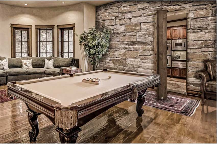 Game room with murphy door, pool table, wood floor, windows, and stone wall cladding