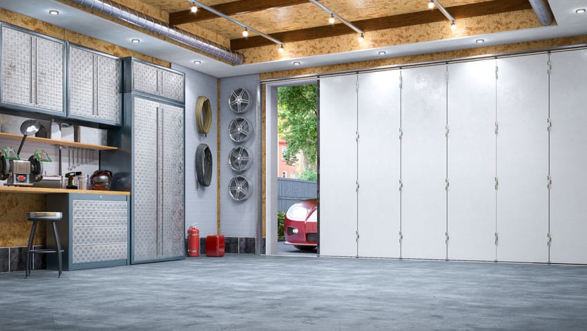 Garage with ceiling lights, epoxy flooring, cabinets, countertop, bifold garage doors, and ceiling lights