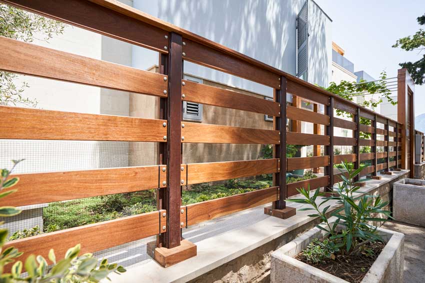 Horizontal fence made of wood with plants near it
