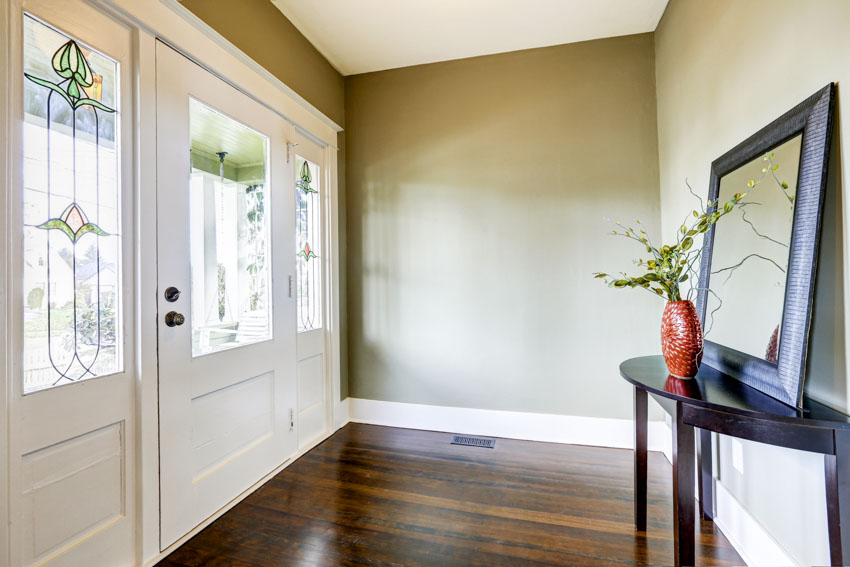 House entranceway with olive wall, stained glass door, and small table