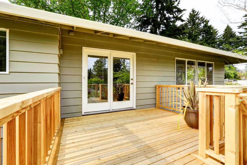 House exterior area with siding glass door, pressure treated wood deck, and railings