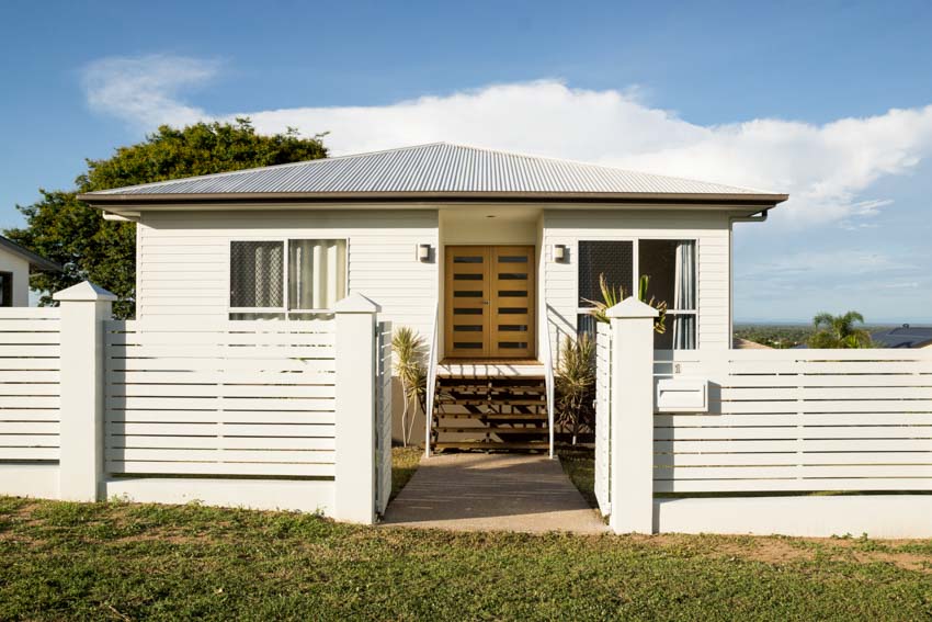 House exterior with vinyl horizontal fence, gate, pitched roof, white walls, and windows