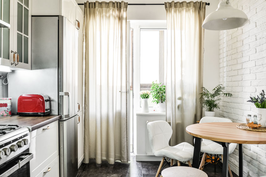 Кухня и столовая со стандартным карнизом для штор, кафельная стена, стол, стулья, комнатные растения и окно