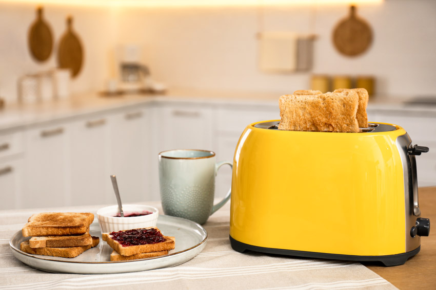 Kitchen counter surface with yellow toaster, plate, and cup