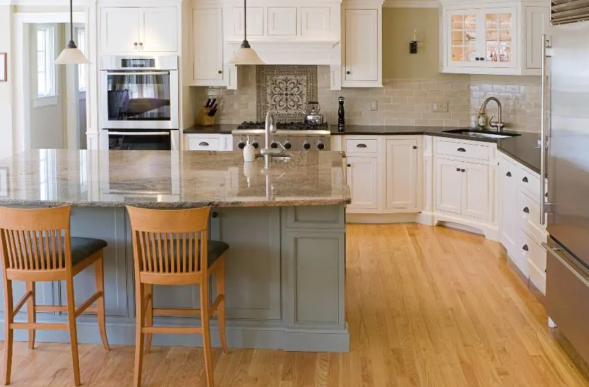 Kitchen interior with island, laminate flooring, granite countertops and inset kitchen cabinets