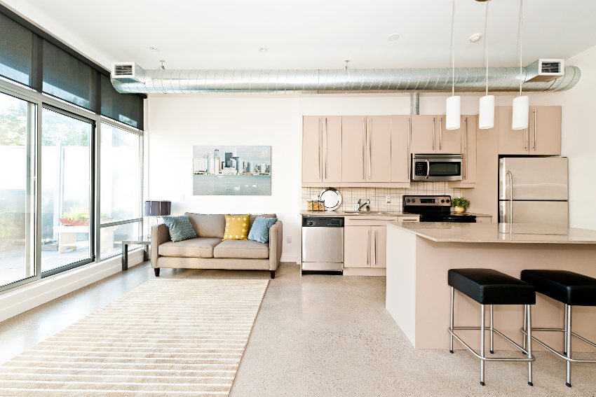 Kitchen with beige cabinets, countertops, sofa and stainless steel appliances