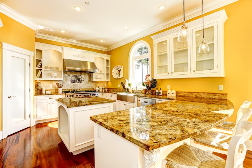 Kitchen with countertops, cabinets, sink, chairs, window, yellow walls, and wood floors