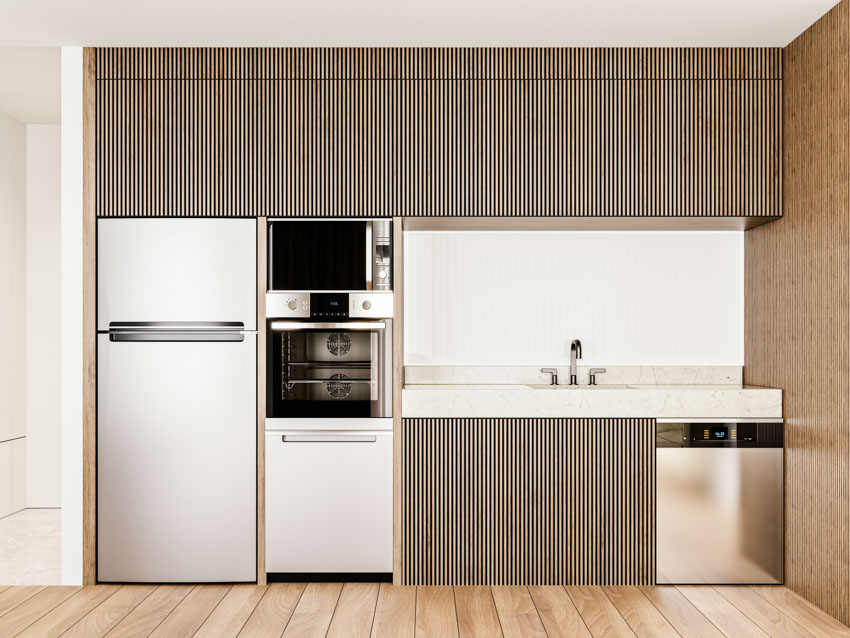 Kitchen with fluted cabinets, wood floor, refrigerator, oven, backsplash, and sink