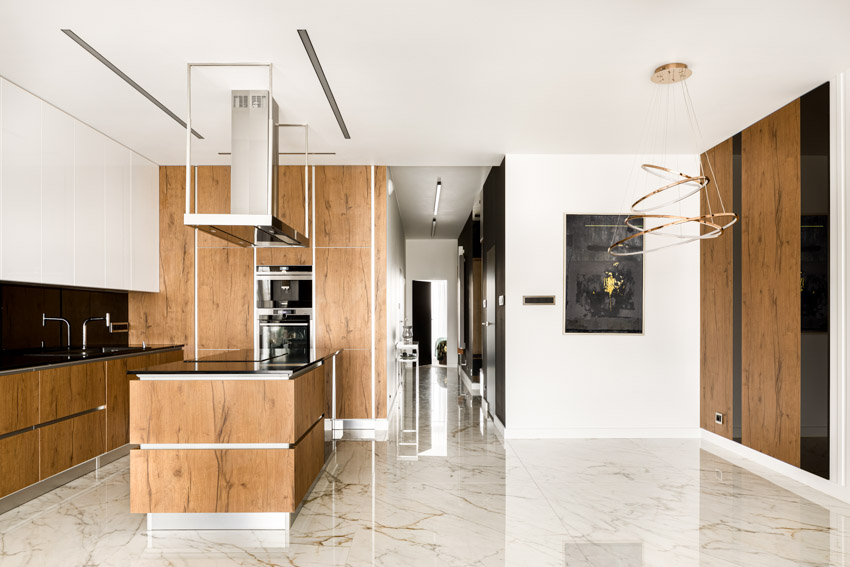 Kitchen with wood cabinets, black tile backsplash and marble tiles
