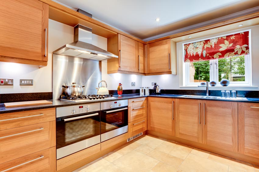 Kitchen with cabinets, dual oven, metal backsplash, countertop and window