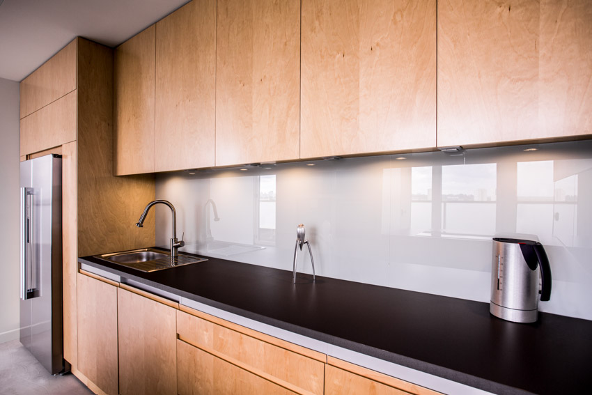 Kitchen with plywood cabinets, black countertops, faucet and sink