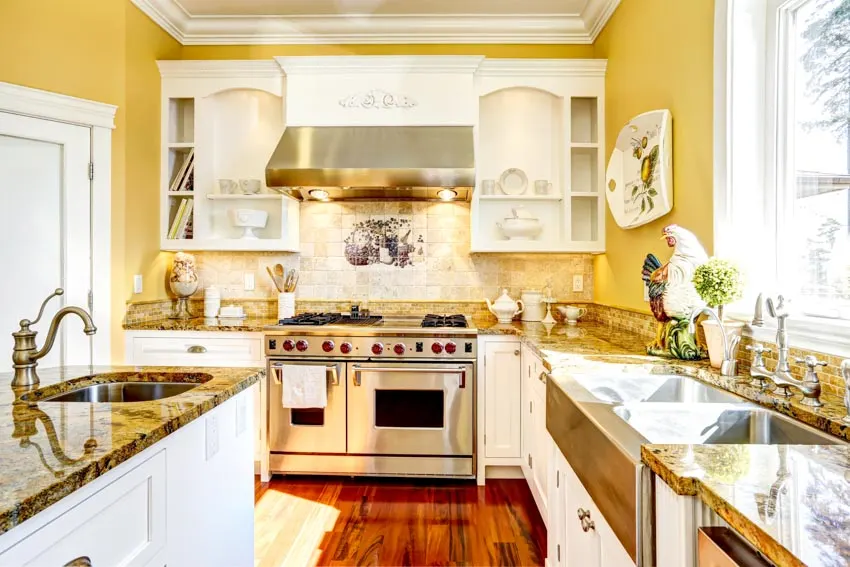 Kitchen with yellow walls, oven, white cabinets, backsplash, sink, countertops, and windows