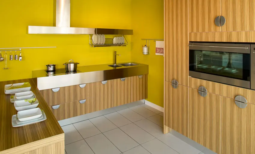 Kitchen with yellow walls, wood cabinets, range hood, oven, and sink