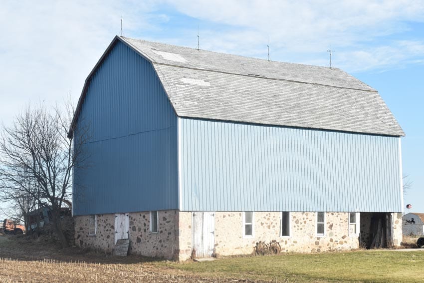 Light blue gambrel barn with windows, and a pitched roof