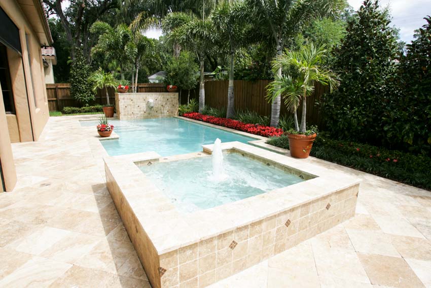 Limestone tile pool deck with jacuzzi and plants surrounding it