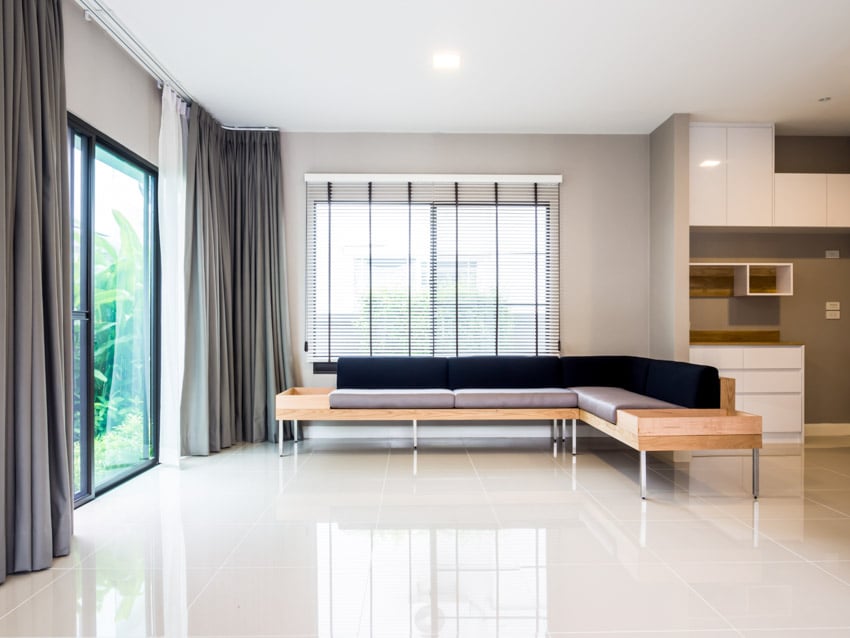 Room with L shaped sofa, glass sliding door, curtains and quartz type flooring