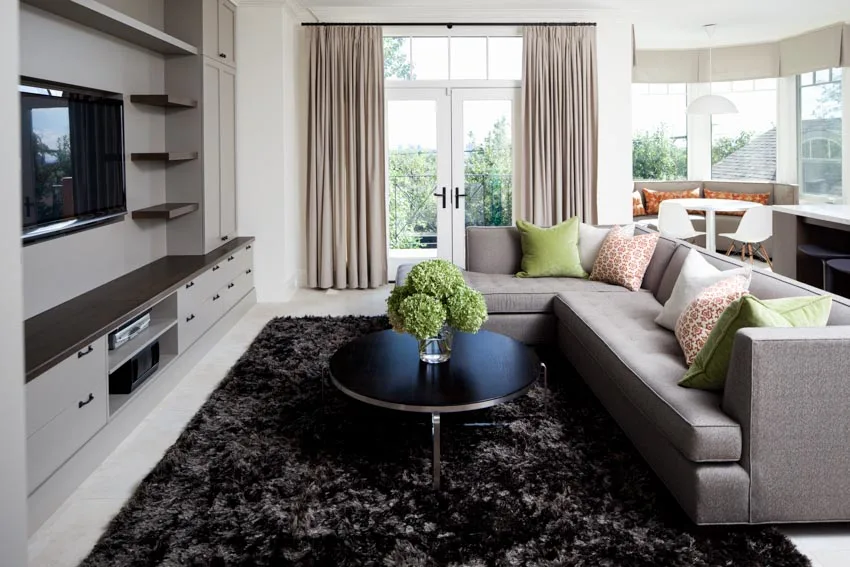 Room with grey sofa, black carpet and earthy hue curtains