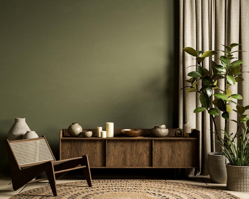 Room with dark olive wall, console table, chair, indoor plant, and curtains