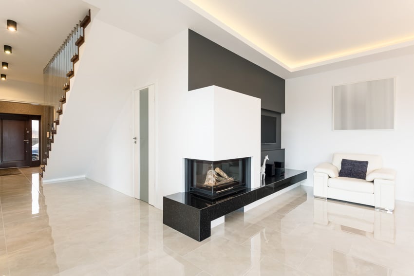 Room with corner fireplace, white arm chair and recessed ceiling lights