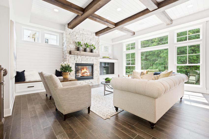 Living room with gas fireplace, wood mantel, hardwood flooring, and coffered beadboard ceiling