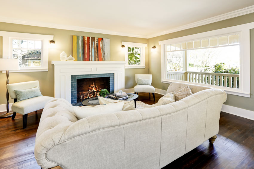 Living room with white sofa, wood floor, fireplace, windows, and olive green wall
